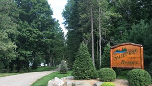 Ein Holzschild für Sunrise Resort, umgeben von einem Kiesweg, Bäumen und gepflegter Bepflanzung.