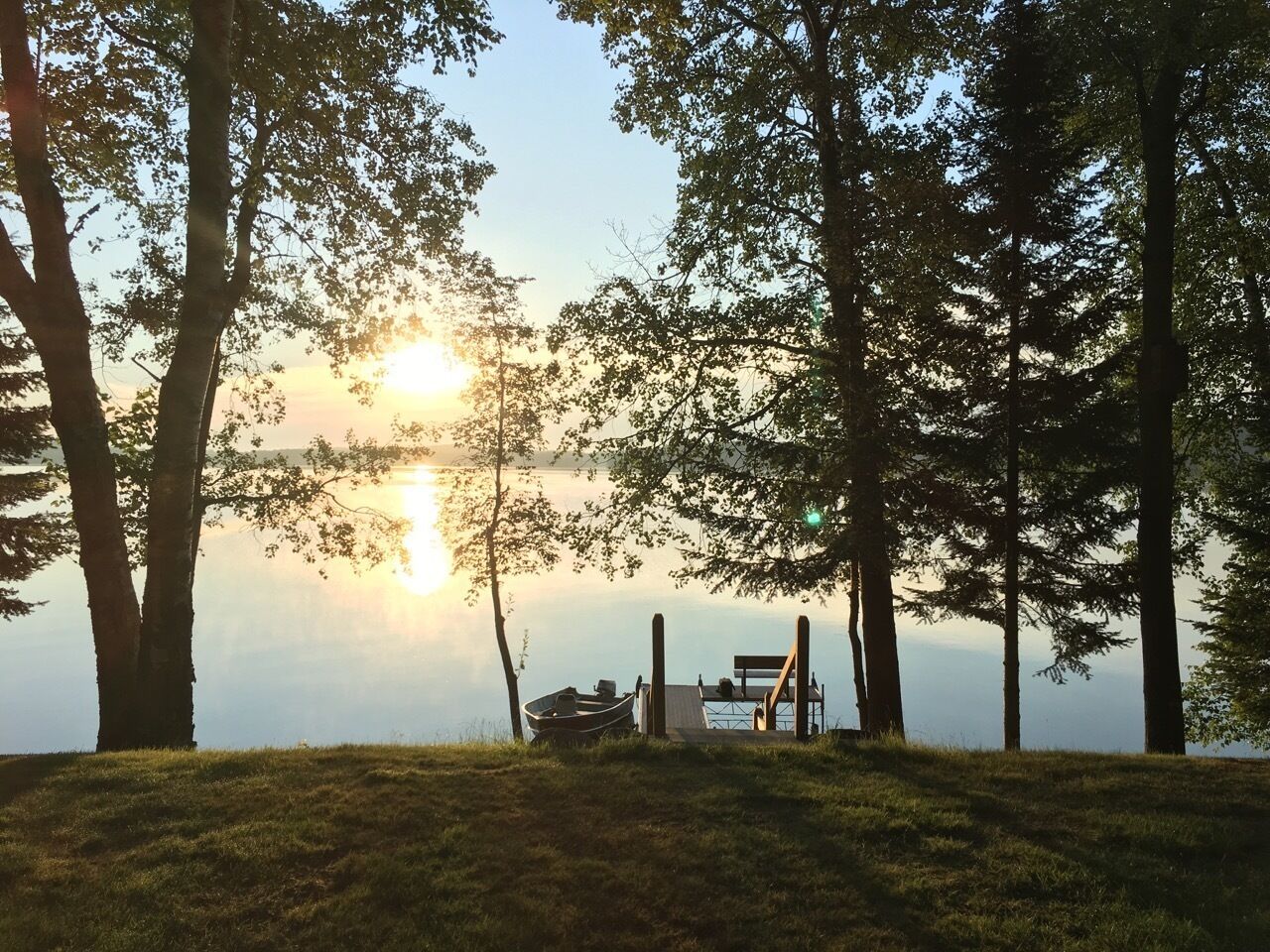 Une vue sur le lac avec un quai et un banc.