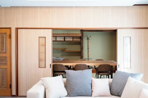 A room with a sofa, a dining table with chairs, and a cabinet with drawers. - Kamifurano Cozy House (Kamifurano-cho, Sorachi District)