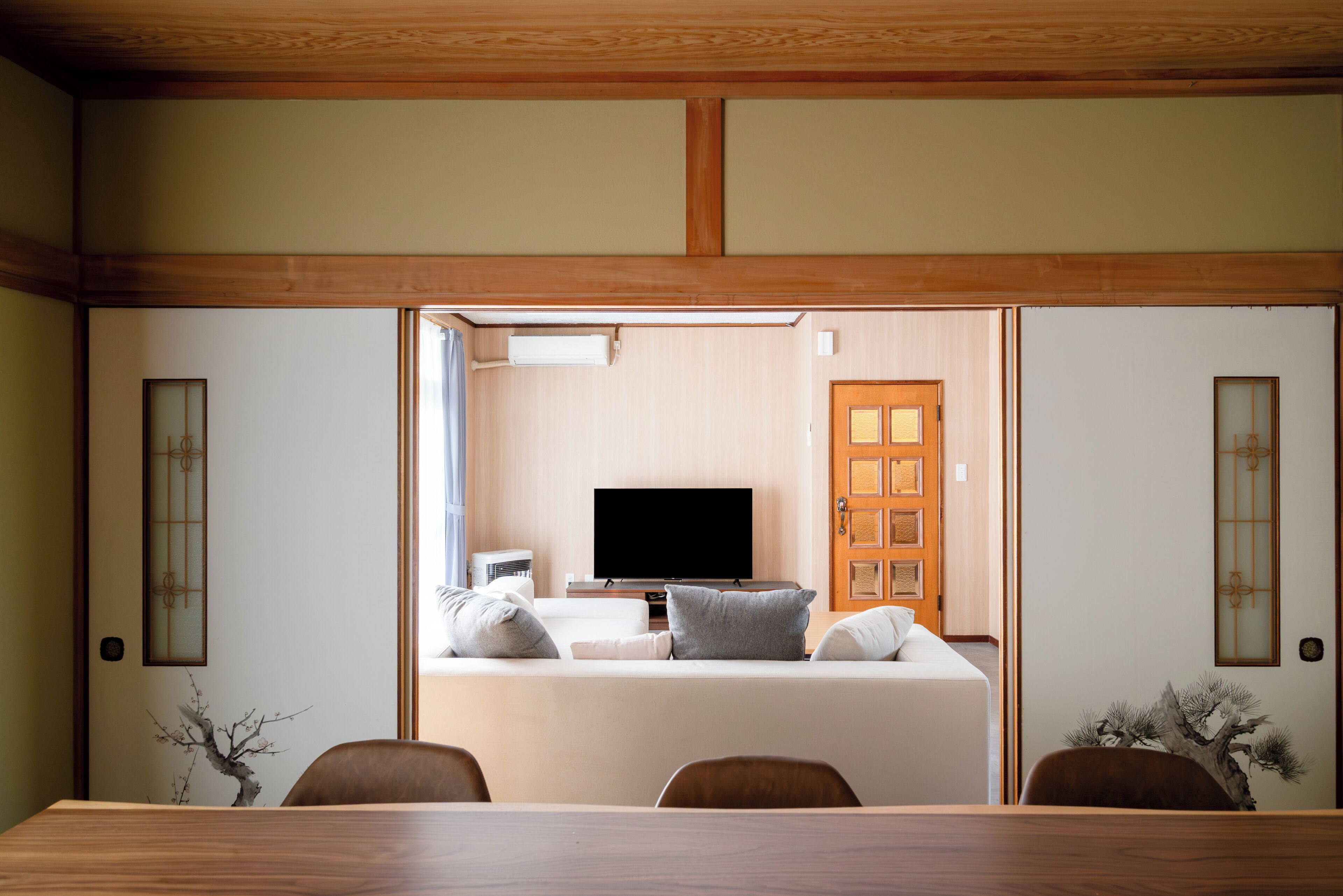 Una habitación tradicional japonesa con suelo de tatami, una mesa baja y un televisor al fondo.