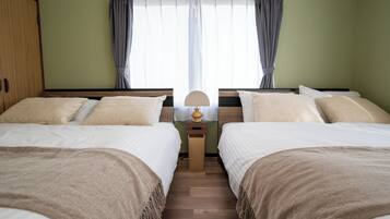 A twin room with two beds, a nightstand, a lamp, and a window with curtains.