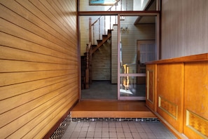 Un pasillo interior de madera con una escalera que sube a un nivel superior.