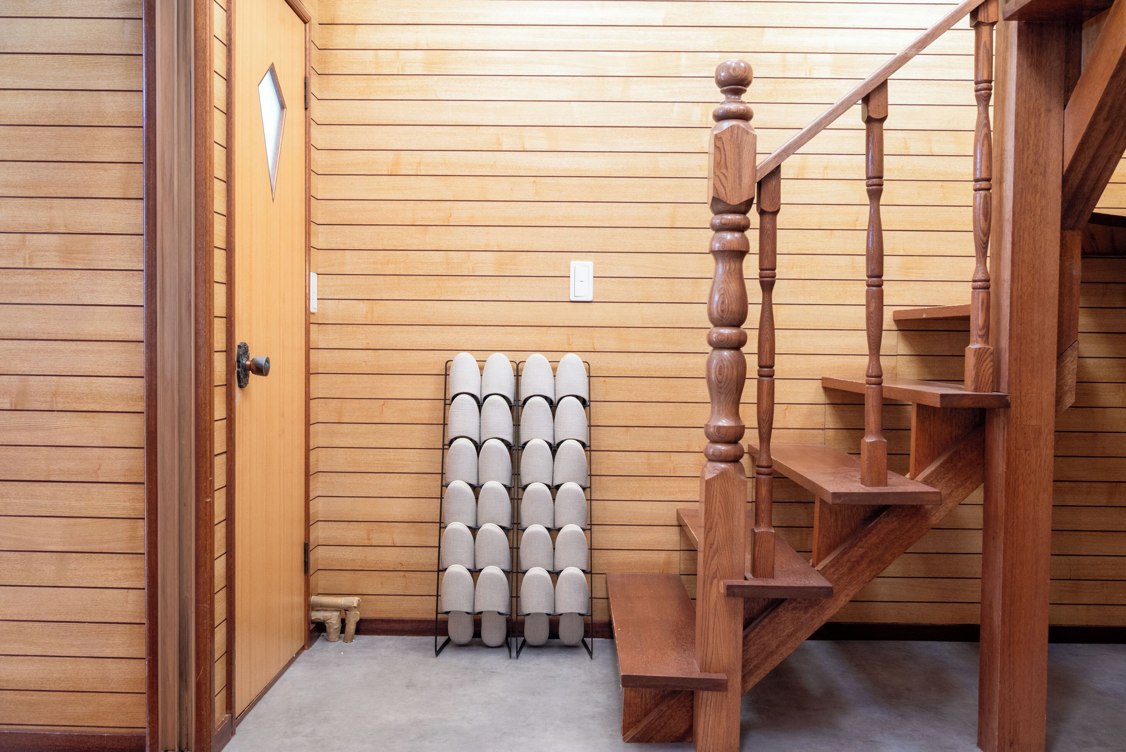 A wooden staircase with a handrail, a wall-mounted light switch, and a radiator.