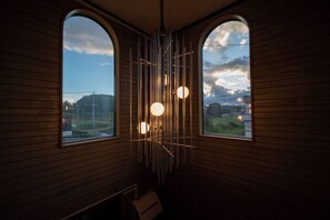 Una habitación con paneles de madera, dos ventanas arqueadas y una lámpara moderna.
