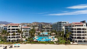 Ett hotellkomplex med flera byggnader, en central pool och ett område vid stranden.