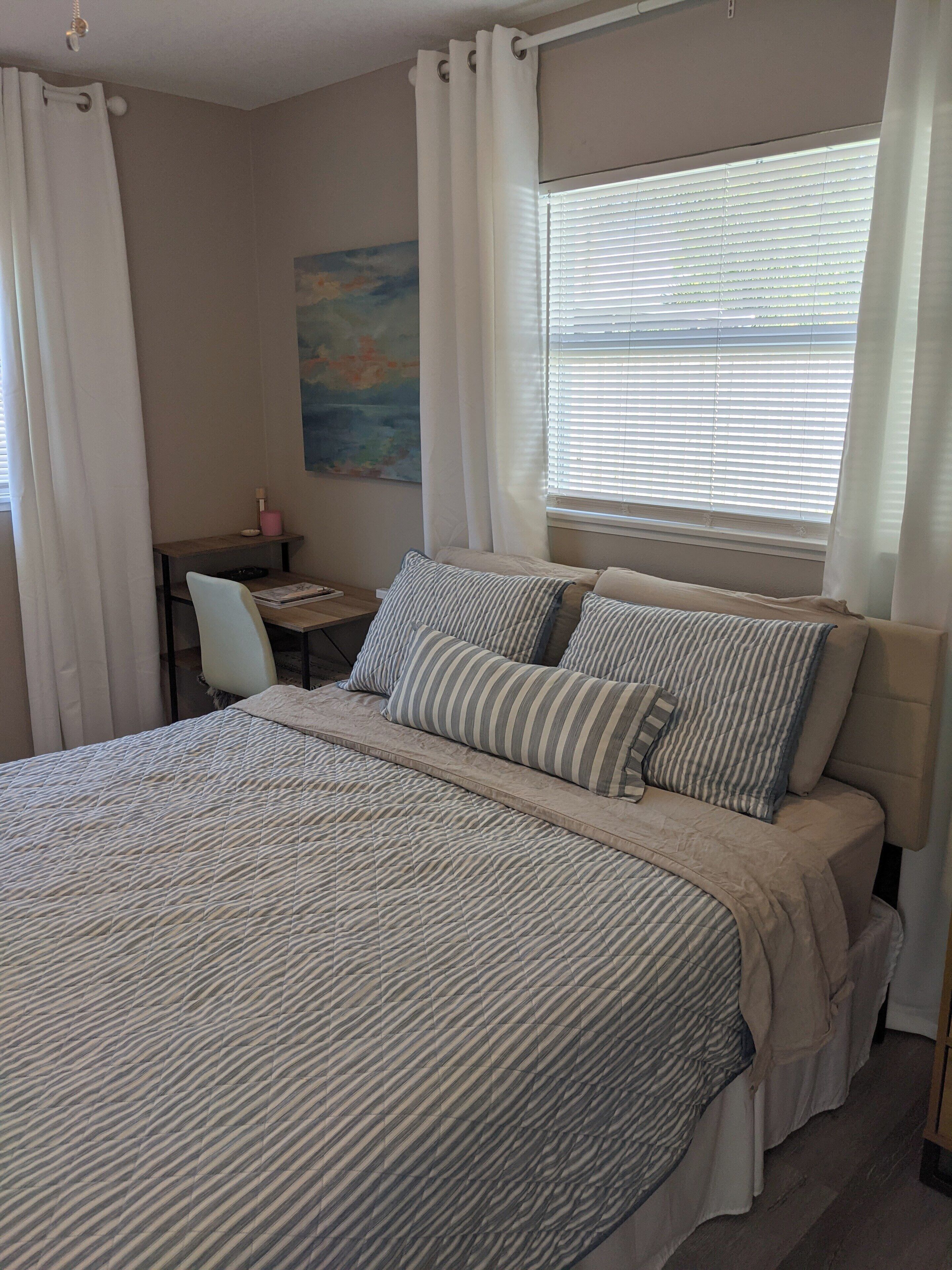 A bedroom with a bed, a desk, and a chair.