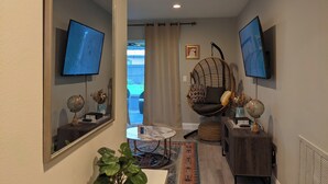 Una sala de estar moderna con televisor, una silla colgante, un globo terráqueo y un espejo.