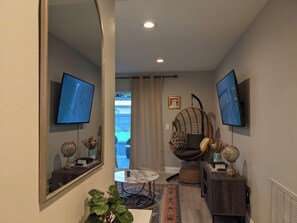 Ein modernes Wohnzimmer mit Fernseher, Hängesessel, Globus und Spiegel.