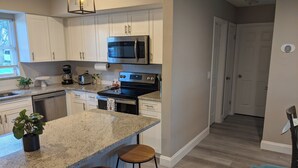 Una cocina moderna con encimeras de granito, electrodomésticos de acero inoxidable y una isla central con taburetes de bar.