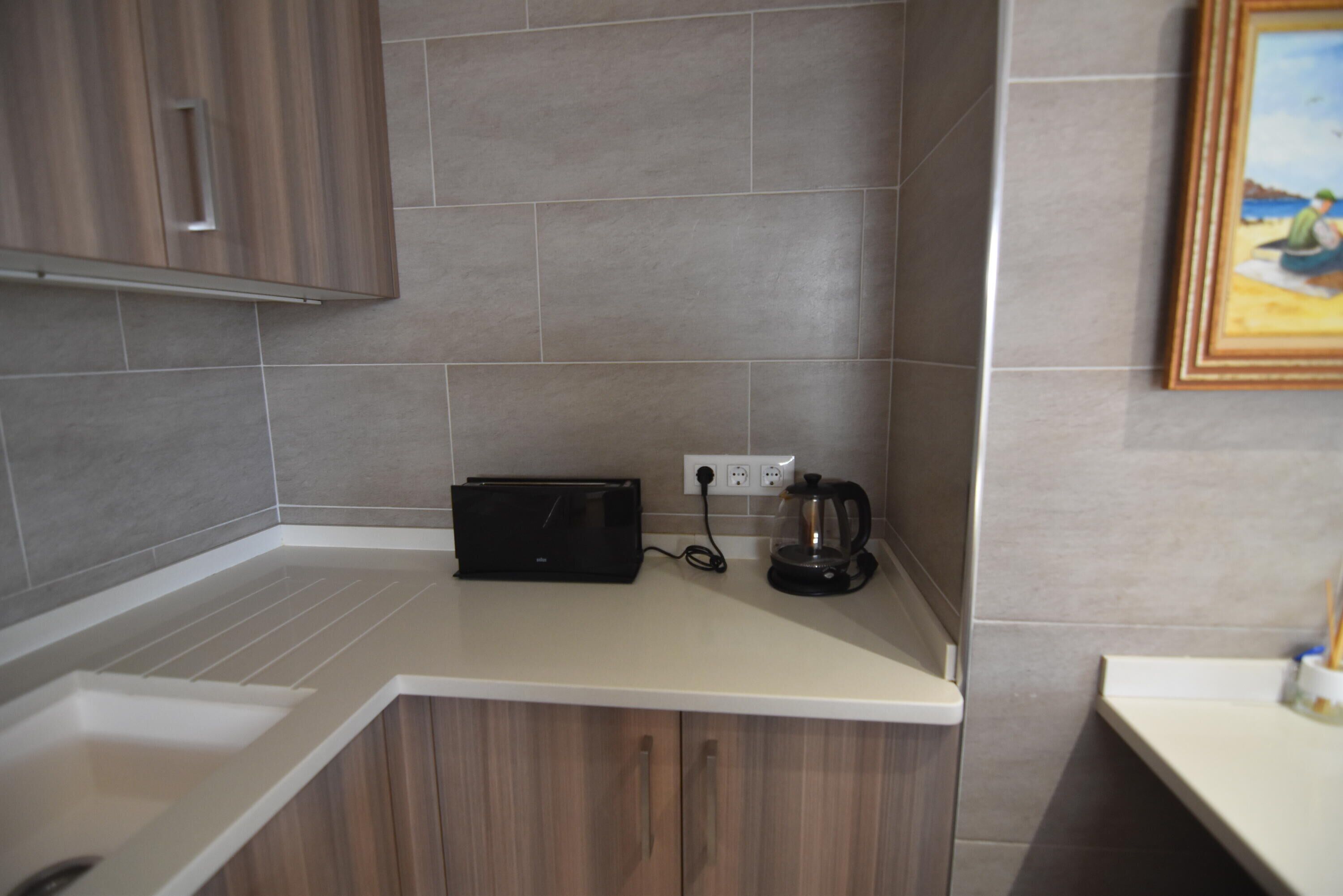 Una cocina con mostrador, tostadora, cafetera y enchufe en la pared.