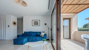 Un salon moderne avec un canapé bleu, une table basse blanche et une plante en pot.