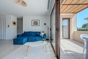 A modern living room with a blue sofa, a white coffee table, and a potted plant. - Le Cocon des Taillades - Appt climatisé (Taillades)