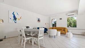 Ein modernes Wohnzimmer mit Essbereich, weißen Wänden und Kunstwerken.