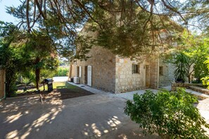 A stone building with a paved driveway, surrounded by trees and greenery. - Le Mas des Aromes - Piscine Privée (Mandelieu-la-Napoule)