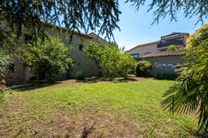 A courtyard with stone buildings, a grassy area, and trees. - Le Mas des Aromes - Piscine Privée (Mandelieu-la-Napoule)