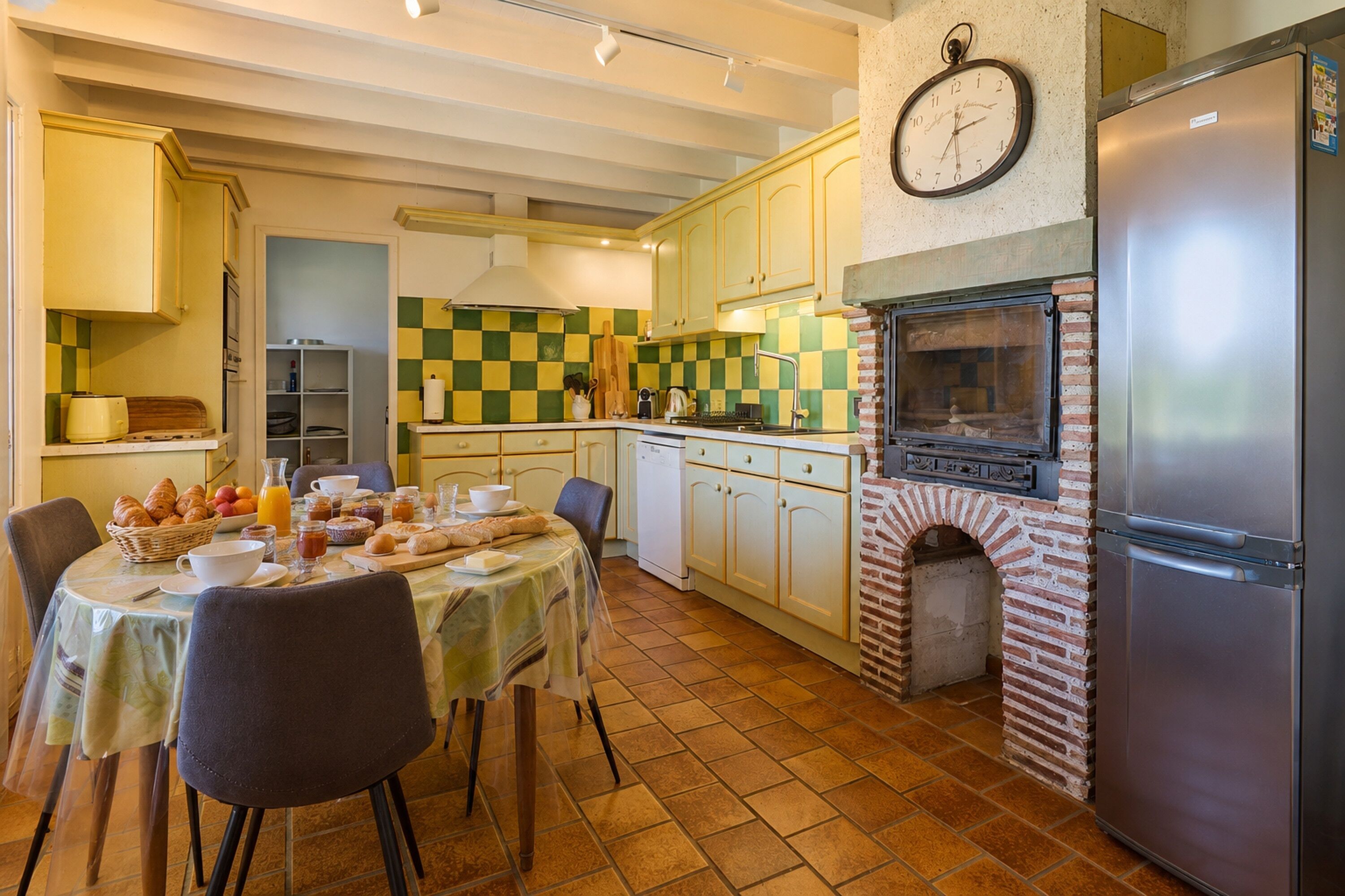 Een keuken met een bakoven, een koelkast en een ontbijttafel gedekt.