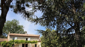 A stone house with a tiled roof, surrounded by trees and a grassy yard. - Le Mounet, charmante maison dans le Pays de Serres (Frespech)