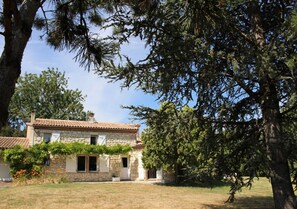 A stone house with a tiled roof, surrounded by trees and a grassy yard. - Le Mounet, charmante maison dans le Pays de Serres (Frespech)