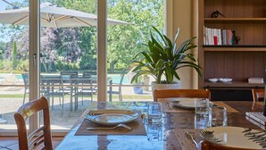 An outdoor dining area with a table set for two, a potted plant, and a bookshelf in the background. - Le Mounet, charmante maison dans le Pays de Serres (Frespech)
