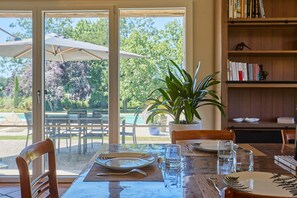 An outdoor dining area with a table set for two, a potted plant, and a bookshelf in the background. - Le Mounet, charmante maison dans le Pays de Serres (Frespech)