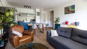 Ein modernes Wohnzimmer mit einem Ledersessel, einem grauen Sofa, einem Glastisch und einem Essbereich mit einem Holztisch und Stühlen.