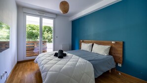 Ein Schlafzimmer mit einem Bett, einem Holz-Kopfteil und Blick durch eine Schiebetür in einen Außenbereich.