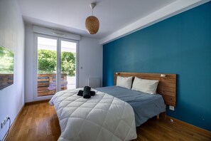 Un dormitorio con cama, cabecero de madera y vista a un espacio exterior por una puerta corredera.