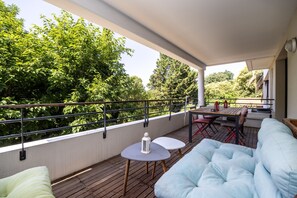 Un espace extérieur abrité, aménagé avec une table et des chaises, un canapé confortable et offrant une vue sur la verdure.