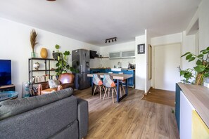A modern kitchen with a dining area, a sofa, and a TV in a living room. - La Parenthèse des Amidonniers - Avec balcon (Toulouse)