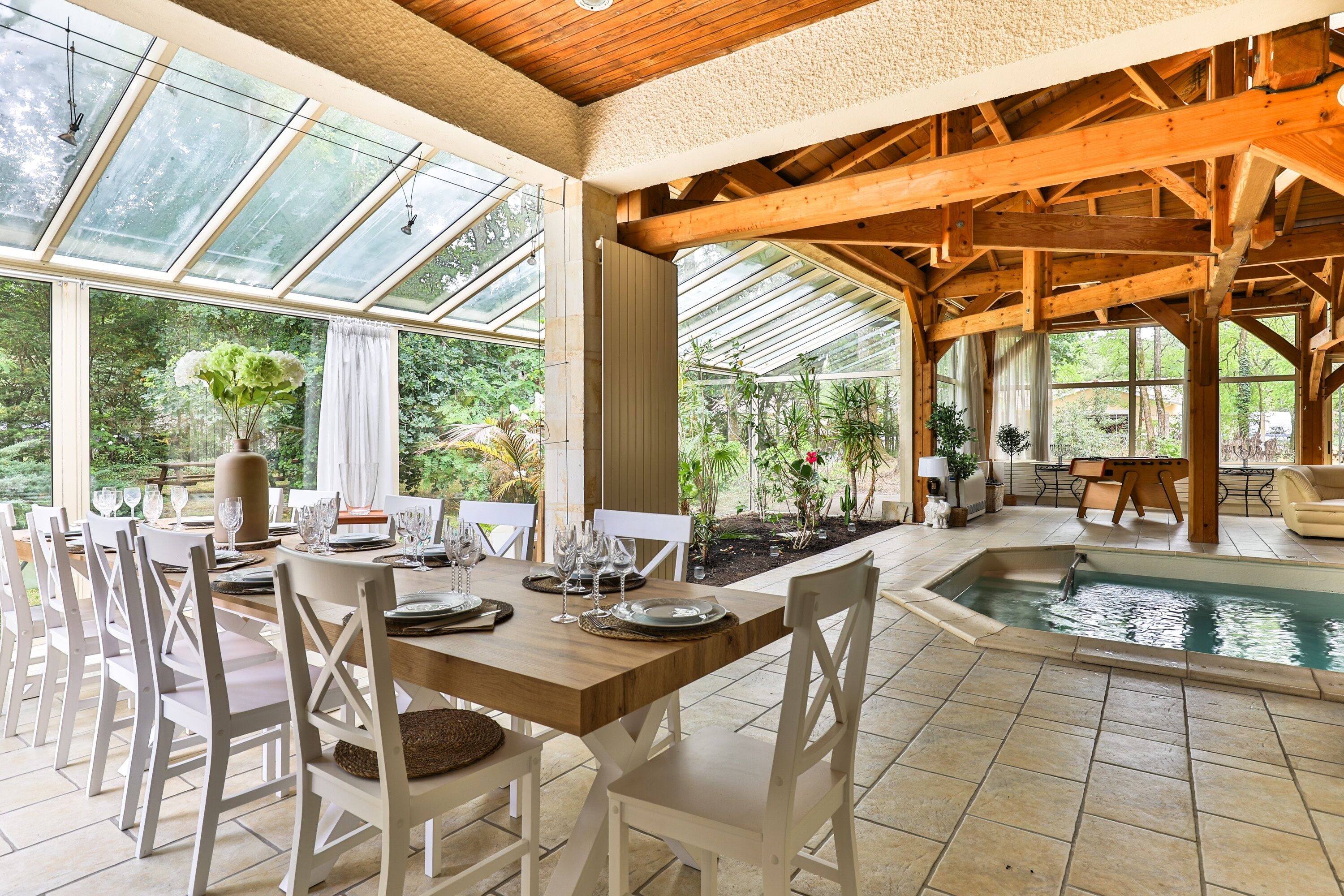 Un comedor con piscina, vigas de madera y ventanas amplias.
