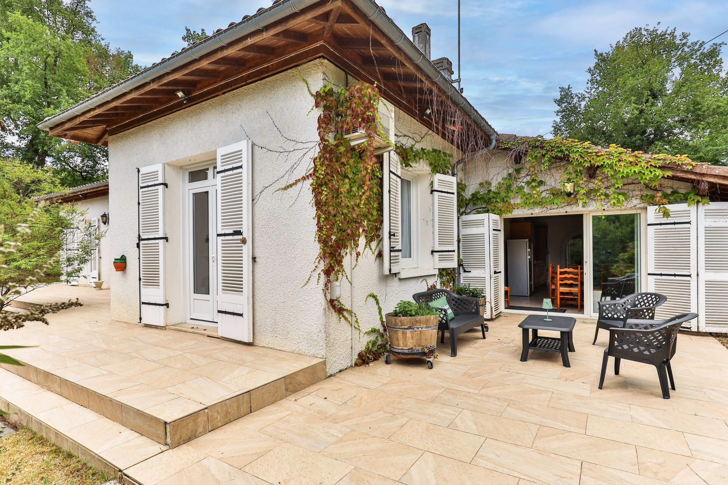 Una casa con patio, mobiliario exterior y jardín.