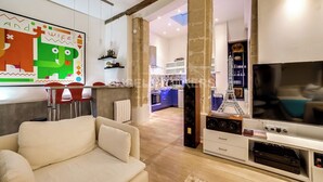 A modern living room with a sofa, a TV, and a kitchen in the background. - LUXURY LOFT IN THE HEART OF PARIS (Paris)