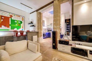 A modern living room with a sofa, a TV, and a kitchen in the background. - LUXURY LOFT IN THE HEART OF PARIS (Paris)