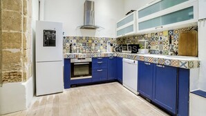 A kitchen with blue cabinets, a white refrigerator, a tiled backsplash, and a stainless steel range hood. - LUXURY LOFT IN THE HEART OF PARIS (Paris)