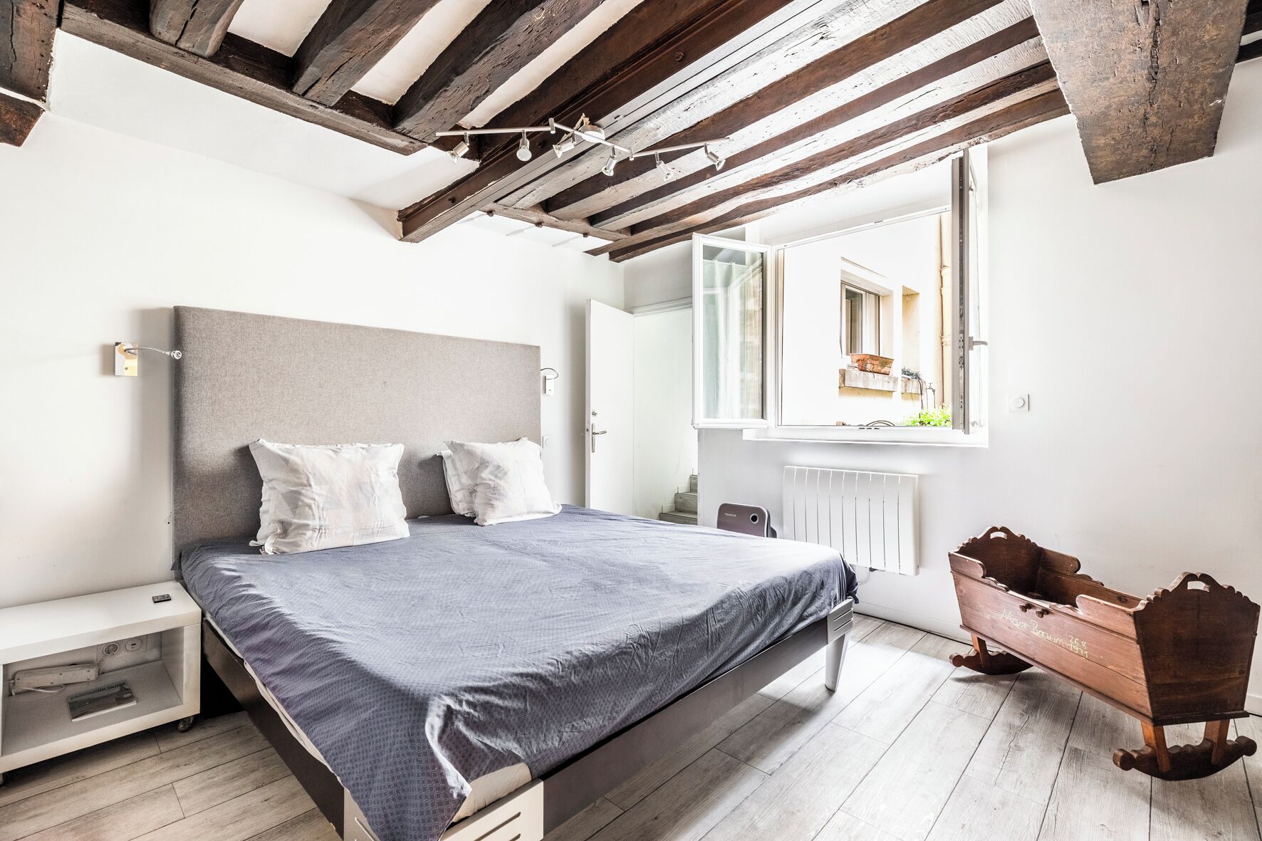 Une chambre à coucher avec un lit, une table de chevet et une commode en bois.