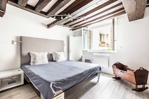 Quarto com cama, mesa de cabeceira e cômoda de madeira.
