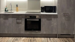 Une cuisine moderne avec des meubles gris, des appareils en acier inoxydable et un plancher en bois.