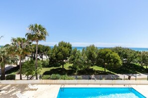 Ein Swimmingpool mit Blick auf das Meer, umgeben von Bäumen und einem Zaun.