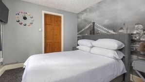 Ein Schlafzimmer mit einem Bett, einer Holztür, einer Wanduhr und einem Stadtbild-Wandgemälde.