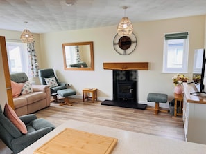 A living room with a sofa, armchair, fireplace, and a small table. - Charming 3 Bedroom Cottage - Garden, WiFi, Parking (Holyhead)