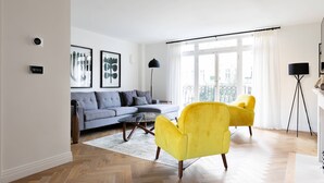 Una sala de estar moderna con un sofá, dos sillones, una mesa de centro y una lámpara de pie.
