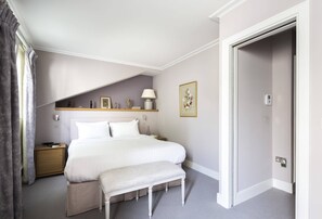 A bedroom with a bed, bedside table, bench, and a door to the right. - Petersham Mews II - Two Bedroom House, Sleeps 4 (London)
