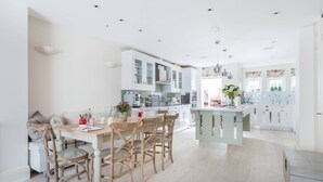 Een moderne keuken met witte kasten, een houten eettafel en een centraal eiland.