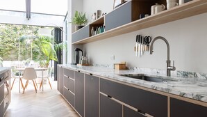A modern kitchen with a large window, built-in shelves, and a marble countertop. - South End Green II - Five Bedroom House, Sleeps 10 (Hampstead)