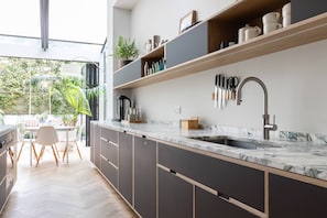 A modern kitchen with a large window, built-in shelves, and a marble countertop. - South End Green II - Five Bedroom House, Sleeps 10 (Hampstead)