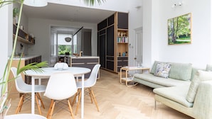 A modern living space with a dining area, a sofa, a bookshelf, and a kitchen in the background. - South End Green II - Five Bedroom House, Sleeps 10 (Hampstead)