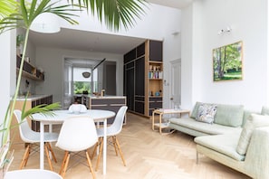 A modern living space with a dining area, a sofa, a bookshelf, and a kitchen in the background. - South End Green II - Five Bedroom House, Sleeps 10 (Hampstead)