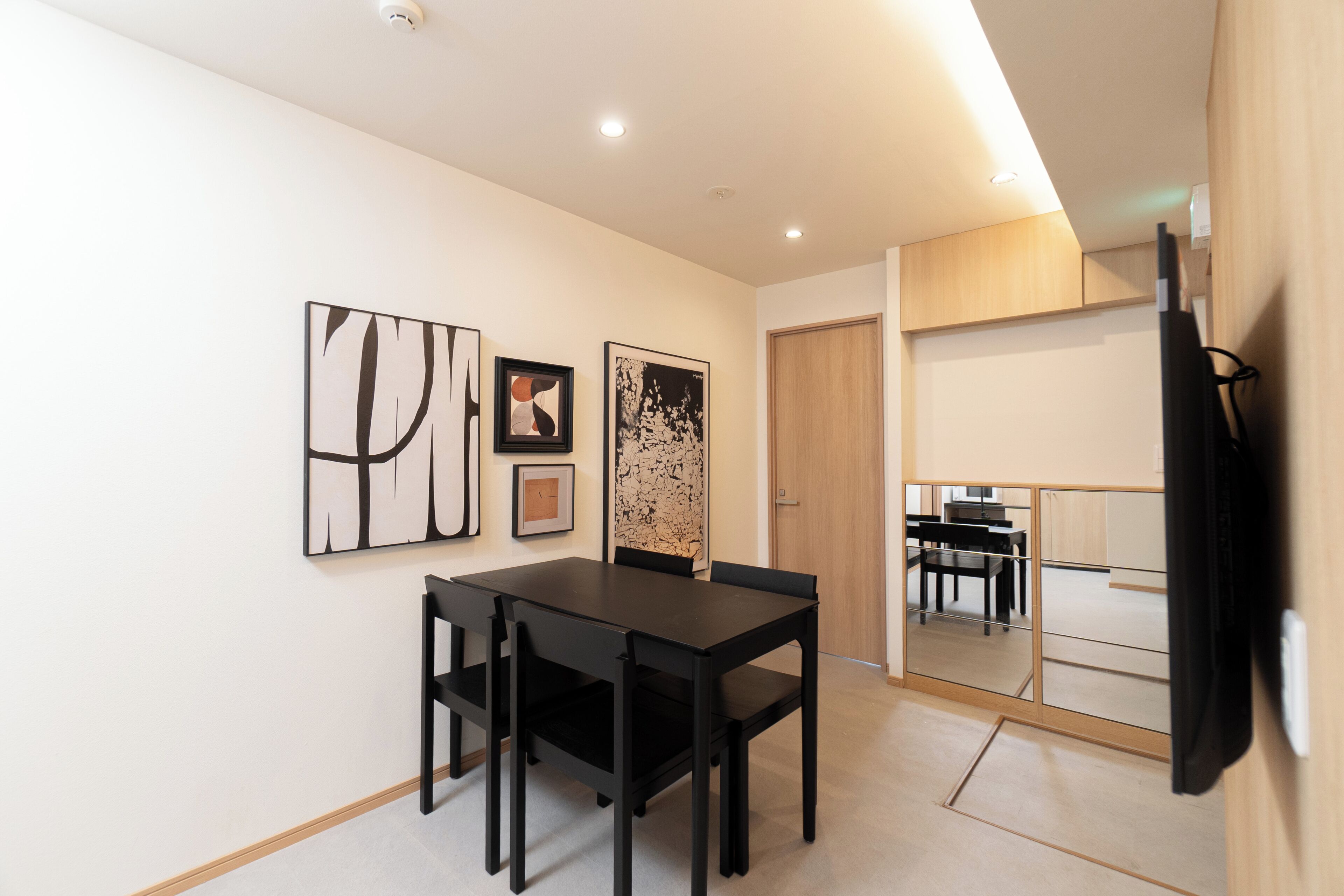 Un comedor con una mesa y sillas, una pared decorada con obras enmarcadas, y una puerta corredera que da a otra habitación.