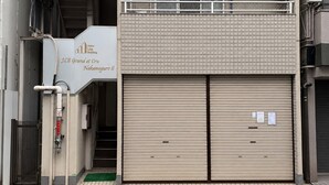Een gebouw met een bord waarop Japan Link Building staat, met een begane grond ingang en een balkon op de tweede verdieping.