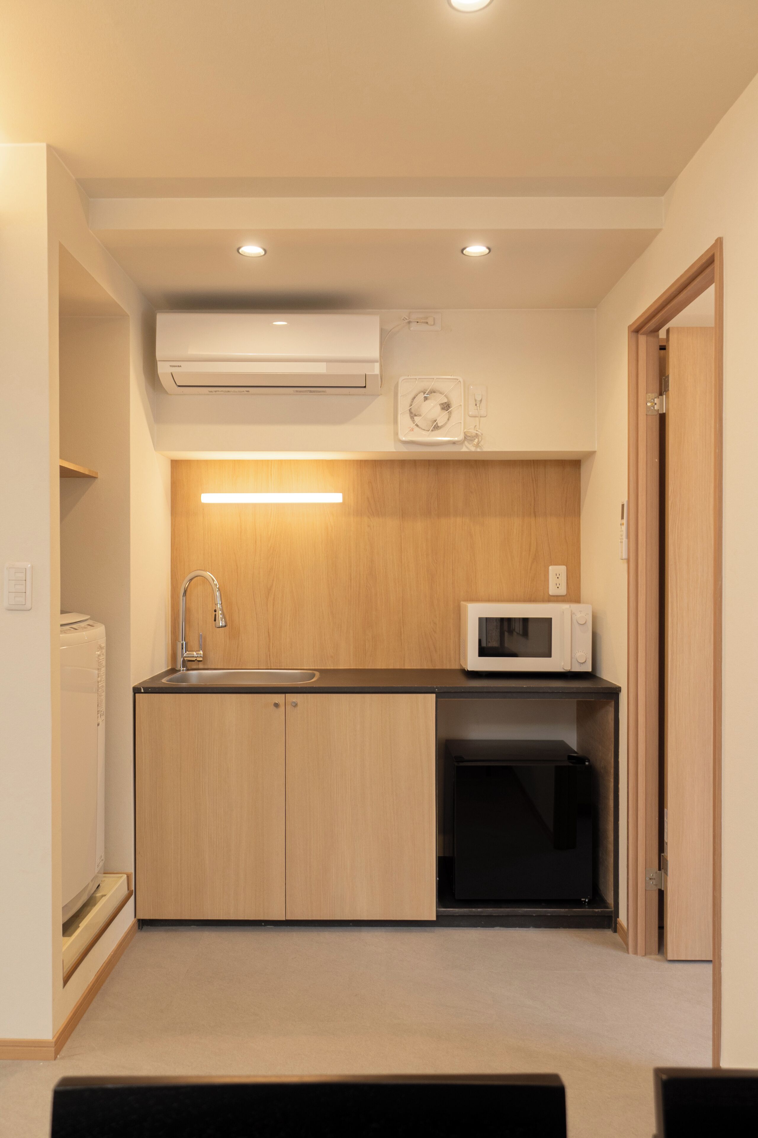 A compact kitchen with a sink, microwave, and built-in oven.